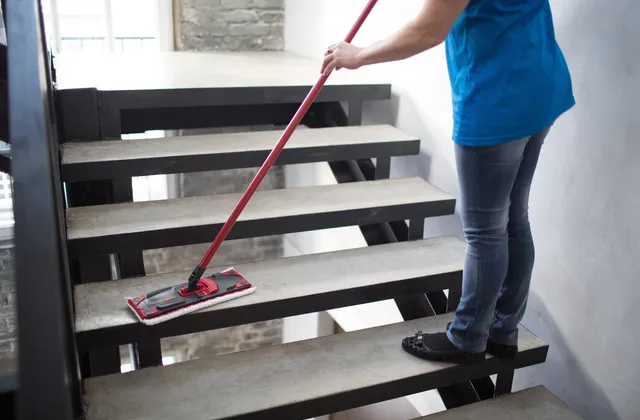 Treppenstufen in einem Hausflur werden mit einem Wischmopp feucht gereinigt.